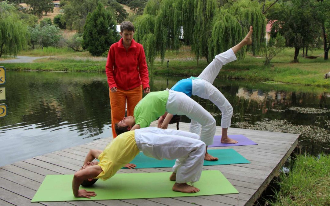 A yoga teacher helping students coming up to the wheel pose