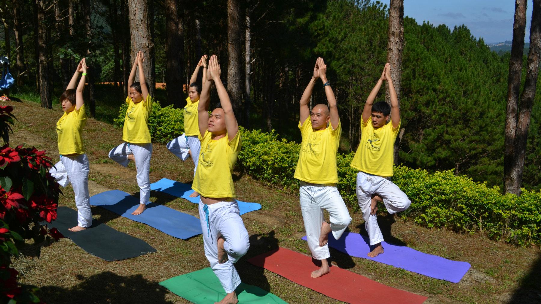 4 students practice Tree Pose by the pond